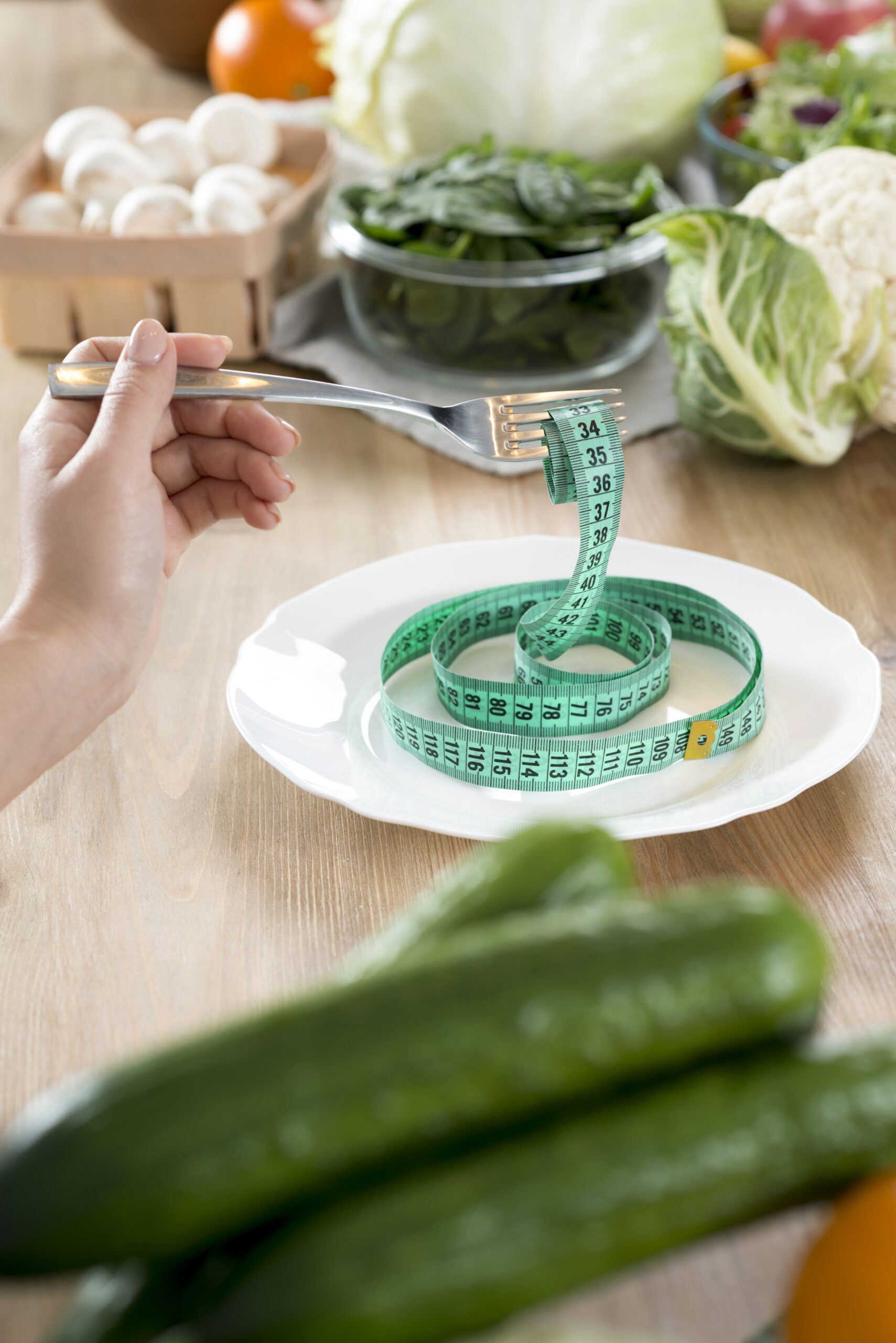 woman-s-hand-holding-fork-with-green-measurement-tape-white-plate-kitchen-counter